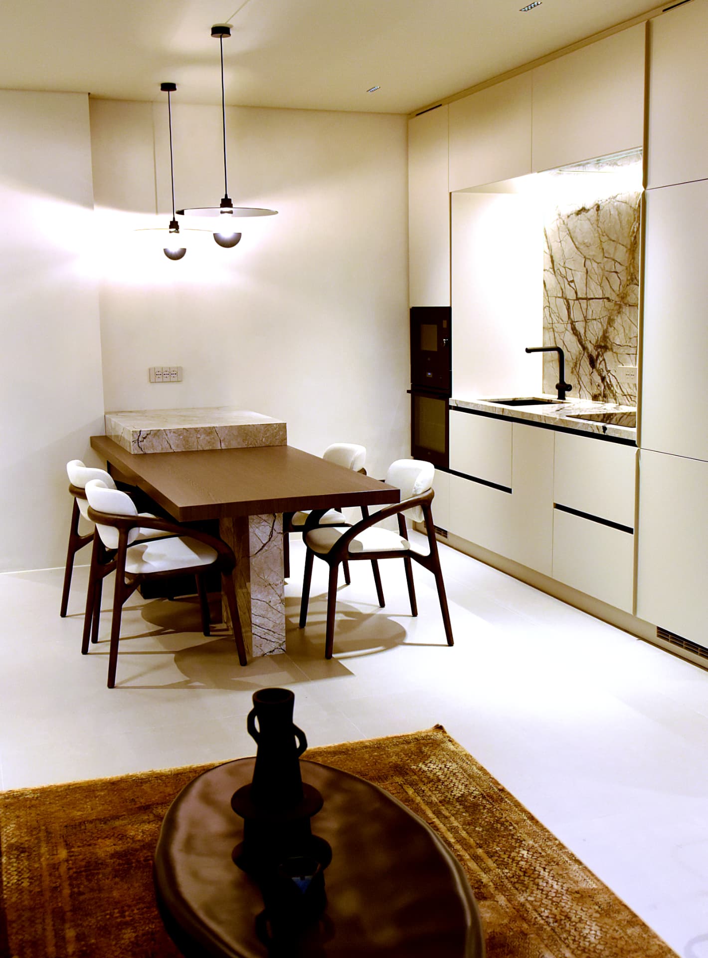 Interno residenziale di pregio con tavolo da pranzo in legno scuro e cucina a vista in marmo